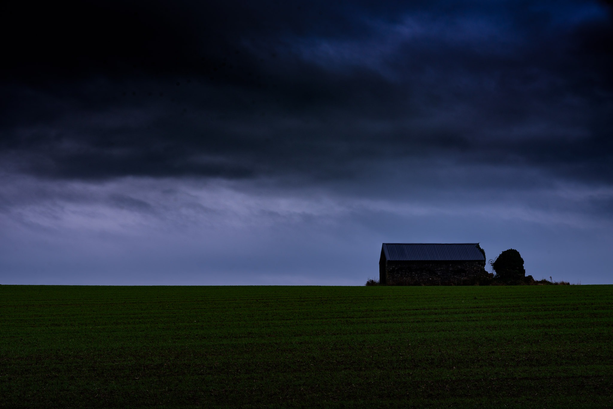A lone barn stands in a field in the nightscape photography portfolio by Charlie Hannah