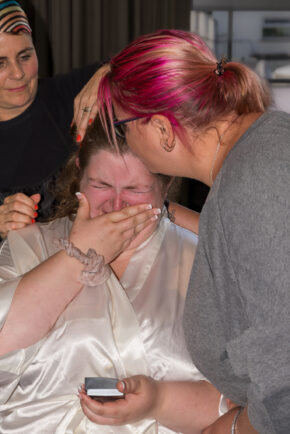 A candid documentary photo capturing an intensely emotional, tearful moment with a bride or bridal party member surrounded by support during morning prep.