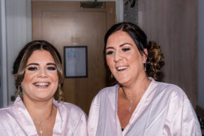Two smiling bridesmaids or bridal party members in matching robes during wedding morning preparation in South Wales.