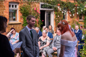 Bride laughing while promising to let the groom watch football occasionally during their wedding ceremony.