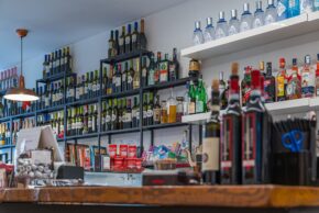 Perugia - September 2023 Still life interior photography of rows of wine and spirit bottles neatly arranged on metal and wooden shelves behind a bar counter.