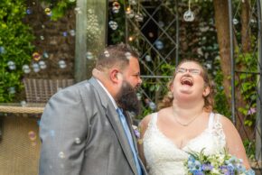 a candid unposed image of the bride and groom laughing behind a curtain of bubbles by Charlie Hannah