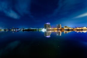 A mesmerising night-time capture of the Cardiff Bay waterfront, featuring glowing modern architecture and crisp water reflections under a starry twilight sky. Long exposure night view of the illuminated Cardiff Bay skyline and architecture reflecting perfectly on the calm water surface.