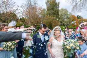 documentary wedding photography capturing the happy couple walking through a shower of confetti