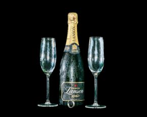 Still life photography of a chilled bottle of Lanson champagne covered in condensation, flanked by two empty champagne flutes and a ring at the base, isolated against a black background.