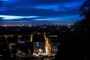 High-angle night view overlooking the illuminated Paris skyline and strelit streets from Montmartre under a deep blue cloudy sky, February 2020.