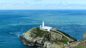 Southstack Lighthouse perched on rugged cliffs surrounded by the blue sea in Anglesey, Wales
