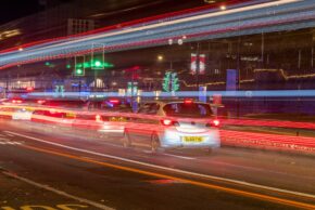 Cardiff - November 2022 Long exposure night photography of an urban street with blue and red emergency light trails from a fire engine streaming past traffic