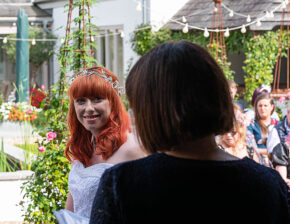 A natural, unposed moment captured mid-ceremony. Candid shot of a smiling red-haired bride looking back during a wedding ceremony by South Wales photographer Charlie Hannah.