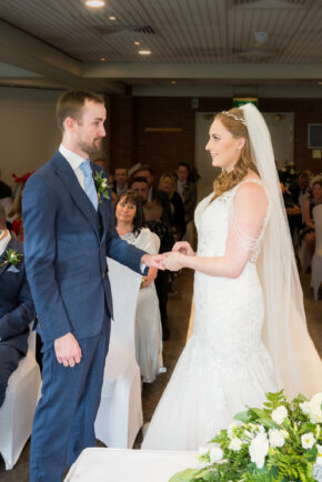 A candid, documentary-style photograph of a couple exchanging rings during their wedding ceremony, captured by Charlie Hannah.