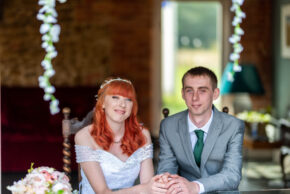 Bride and groom holding hands and smiling during the marriage register signing ceremony.