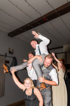 Groom hoisted onto shoulders during wedding celebrations and dancing during the dancing at the night time shenanigans.