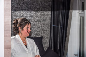 A candid reflection of a bride getting ready in a mirror before her wedding ceremony.