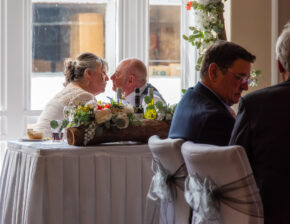 Bride and groom sharing a quiet, tender moment across the top table during their wedding reception in Tongwynlais, captured candidly by documentary wedding photographer Charlie Hannah.