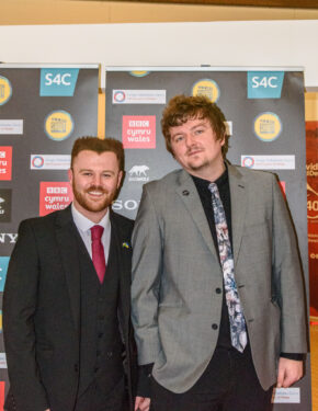 Filmmaker Luke Davies and music producer Cal Roberts posing in front of media backdrops at an event in Cardiff, photographed by South Wales event photographer Charlie Hannah