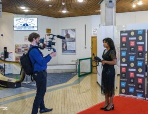 A videographer filming an interview on the red carpet in front of media backdrops at St David's Hall in Cardiff, photographed by South Wales event photographer Charlie Hannah