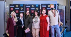 Group of Ukrainian refugees and documentary makers posing in front of media backdrops in Wales, photographed by South Wales event photographer Charlie Hannah