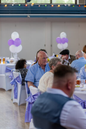 Candid wedding guest sitting at a reception table at Stourbridge Registry Office, caught on camera by documentary wedding photographer Charlie Hannah after claiming he would never be photographed.