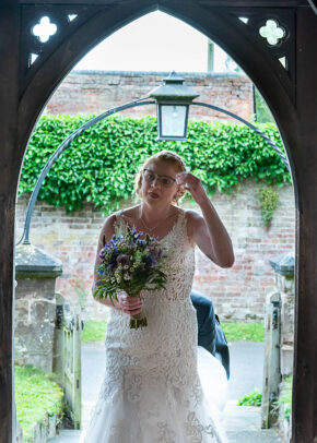 Bride adjusting her hair while holding a bouquet under a wooden archway at the Gemma and Martin wedding, photographed by South Wales wedding photographer Charlie Hannah
