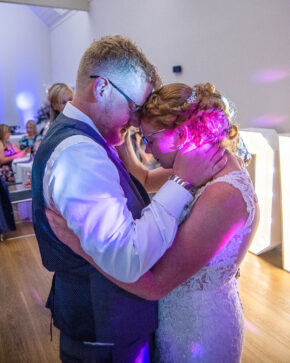 Bride and groom sharing a tender moment with foreheads touching during their first dance under moody lighting, photographed by South Wales wedding photographer Charlie Hannah