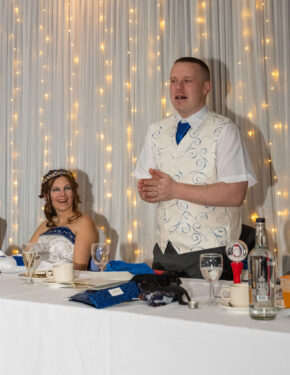 Groom speaking at the top table with a smiling bride looking on during wedding speeches, captured by South Wales wedding photographer Charlie Hannah at The Belfry Nottingham