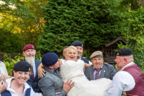 Wedding party members wearing berets playfully lifting the bride during the Tracy and Jim wedding celebration, photographed by South Wales wedding photographer Charlie Hannah
