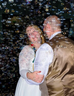 Bride and groom laughing together surrounded by floating bubbles during their first dance, captured by South Wales wedding photographer Charlie Hannah