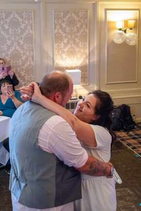 Bride and groom dancing closely while guests take photos on phones during their evening reception, photographed by South Wales wedding photographer Charlie Hannah