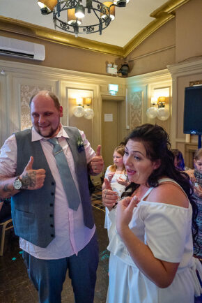 Groom giving double thumbs up and laughing alongside the bride during their wedding reception, photographed by South Wales wedding photographer Charlie Hannah